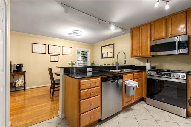 1445 Monroe Dr NE Unit 14B, Atlanta, GA 30324 - kitchen with stainless steel appliances, rail lighting, a peninsula, and brown cabinetry