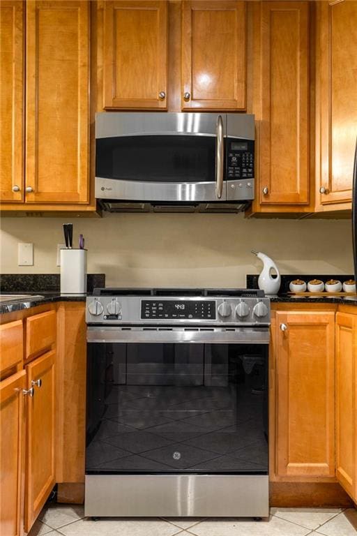 1445 Monroe Dr NE Unit 14B, Atlanta, GA 30324 - kitchen featuring stainless steel appliances, light tile patterned flooring, dark stone counters, and brown cabinets