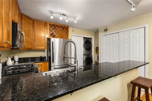 1445 Monroe Dr NE Unit 14B, Atlanta, GA 30324 - kitchen featuring estacked washer and dryer, rail lighting, freestanding refrigerator, brown cabinetry, and a peninsula