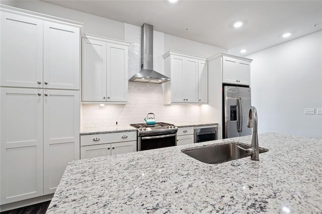 kitchen with white cabinetry, appliances with stainless steel finishes, light stone counters, tasteful backsplash, and wall chimney exhaust hood