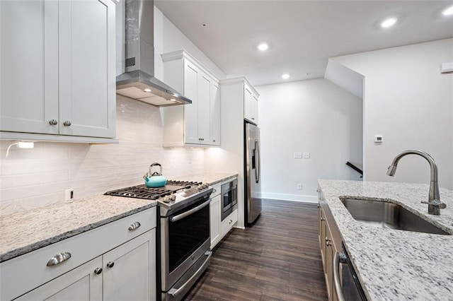 kitchen featuring dark wood-type flooring, appliances with stainless steel finishes, wall chimney exhaust hood, white cabinets, and light stone counters