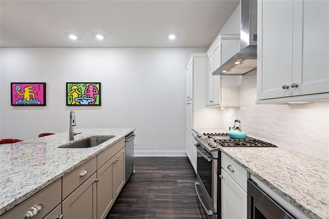 kitchen featuring wall chimney exhaust hood, dark hardwood / wood-style flooring, stainless steel appliances, and light stone counters