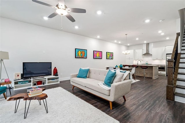 living room featuring dark wood-type flooring, sink, and ceiling fan with notable chandelier