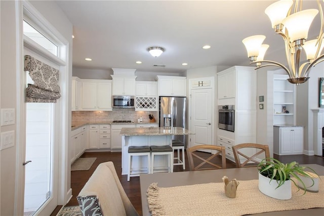 3678 Cresswind Pkwy SW, Gainesville, GA 30504 - kitchen with stainless steel appliances, white cabinetry, a kitchen island, light stone countertops, and a breakfast bar area