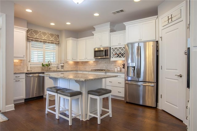 3678 Cresswind Pkwy SW, Gainesville, GA 30504 - kitchen featuring stainless steel appliances, white cabinetry, a center island, decorative backsplash, and a kitchen bar