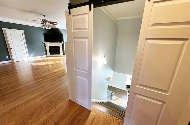 interior space with a barn door, crown molding, and wood-type flooring