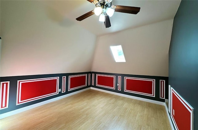 bonus room with light hardwood / wood-style floors, a skylight, and ceiling fan