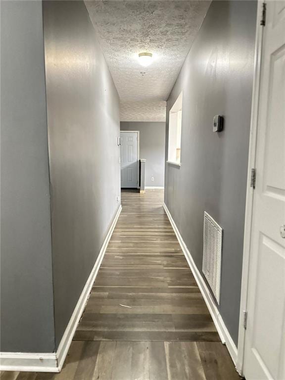 hallway featuring dark hardwood / wood-style flooring and a textured ceiling