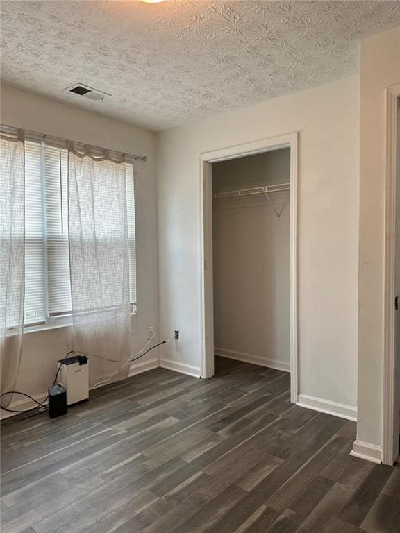 unfurnished bedroom with a closet, dark wood-type flooring, and a textured ceiling