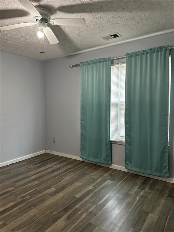 empty room with plenty of natural light, ceiling fan, and dark hardwood / wood-style flooring