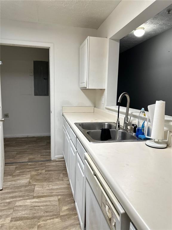 kitchen with white cabinets, stainless steel dishwasher, sink, and a textured ceiling