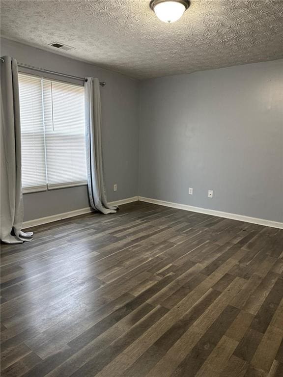 spare room with a textured ceiling and dark hardwood / wood-style flooring