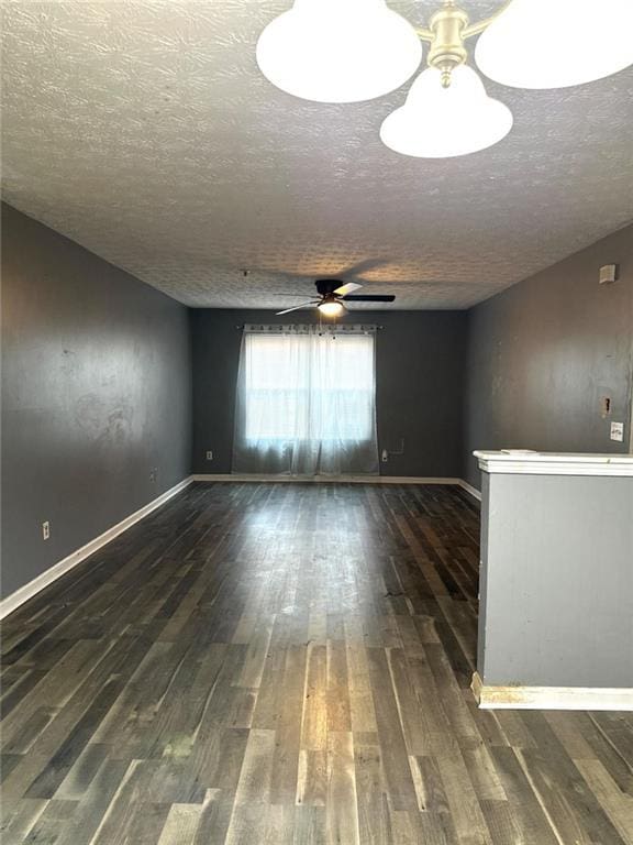 spare room with a textured ceiling, ceiling fan, and dark wood-type flooring