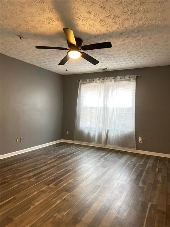 unfurnished room with a wealth of natural light, ceiling fan, and a textured ceiling