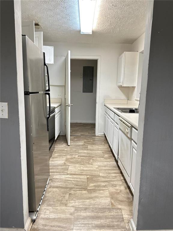 kitchen with appliances with stainless steel finishes, a textured ceiling, sink, white cabinets, and electric panel