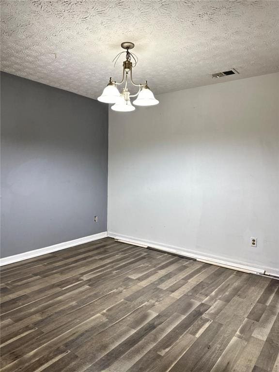 unfurnished room with dark hardwood / wood-style flooring, a chandelier, and a textured ceiling