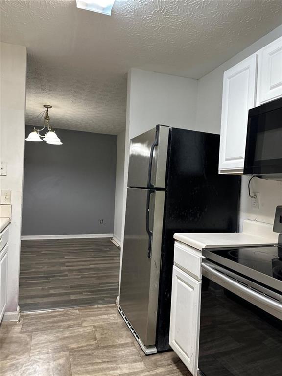 kitchen with light wood-type flooring, a textured ceiling, pendant lighting, white cabinets, and stainless steel electric range