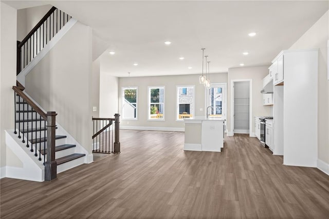 kitchen featuring under cabinet range hood, dark wood-type flooring, white cabinetry, light countertops, and stainless steel range with electric stovetop