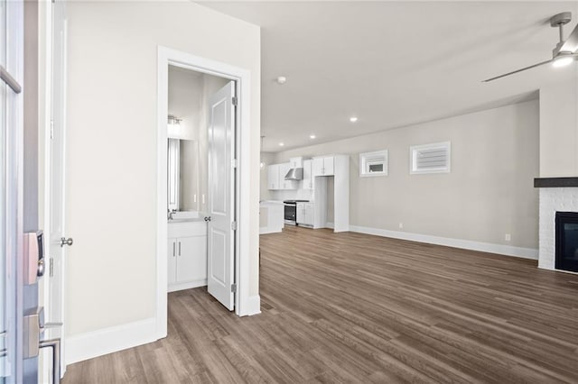 unfurnished living room with dark wood-style flooring, a fireplace, recessed lighting, a ceiling fan, and baseboards