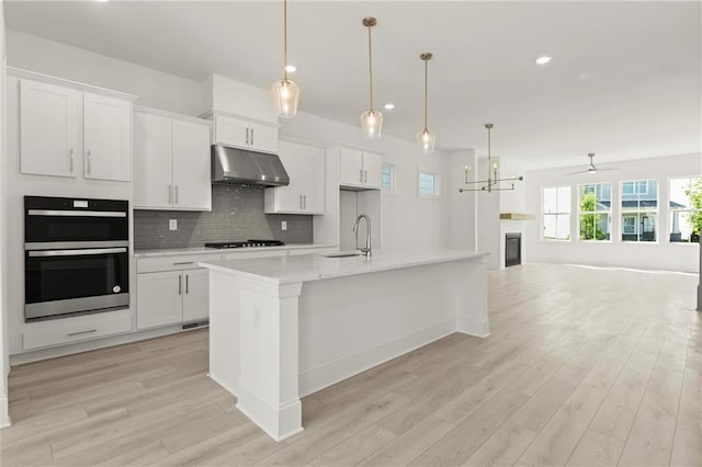 1937 Quarry Park Pl NW, Atlanta, GA 30318 - kitchen with under cabinet range hood, stainless steel double oven, a sink, light wood-style floors, and recessed lighting