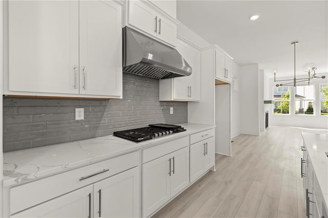 1937 Quarry Park Pl NW, Atlanta, GA 30318 - kitchen with under cabinet range hood, stainless steel gas stovetop, white cabinetry, light wood-style floors, and light stone counters