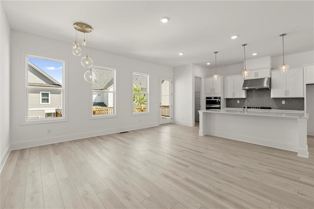 1937 Quarry Park Pl NW, Atlanta, GA 30318 - kitchen with under cabinet range hood, light countertops, decorative backsplash, baseboards, and white cabinets