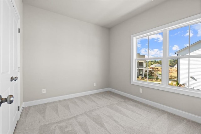 unfurnished room featuring light carpet and baseboards