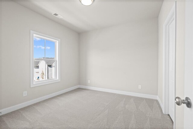 spare room featuring light colored carpet, visible vents, and baseboards