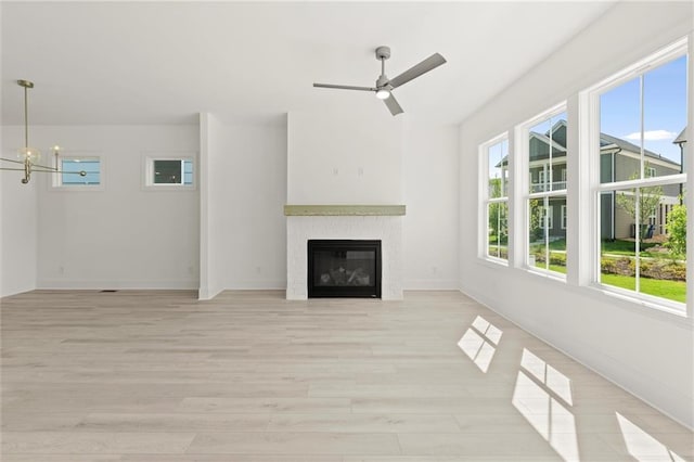 1937 Quarry Park Pl NW, Atlanta, GA 30318 - unfurnished living room with light wood-type flooring, a ceiling fan, a glass covered fireplace, baseboards, and a chandelier