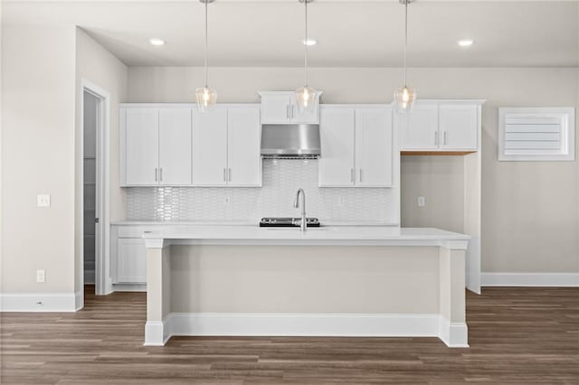 kitchen with tasteful backsplash, a center island with sink, white cabinets, dark wood-style floors, and under cabinet range hood