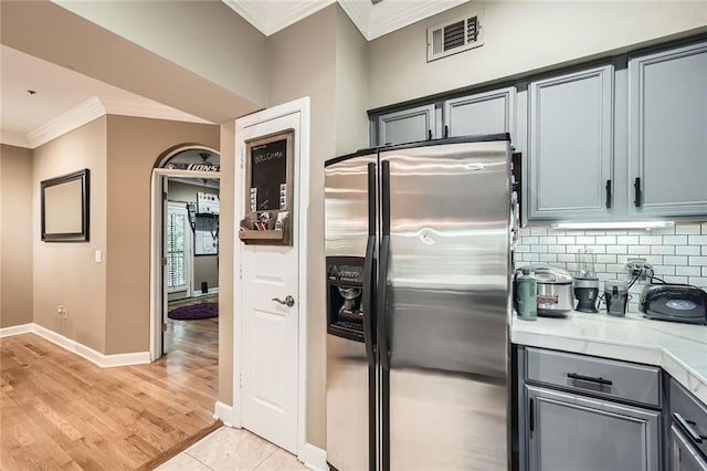 3777 Peachtree Rd NE Unit 438, Brookhaven, GA 30319 - kitchen with stainless steel refrigerator with ice dispenser, ornamental molding, light countertops, backsplash, and light wood-type flooring