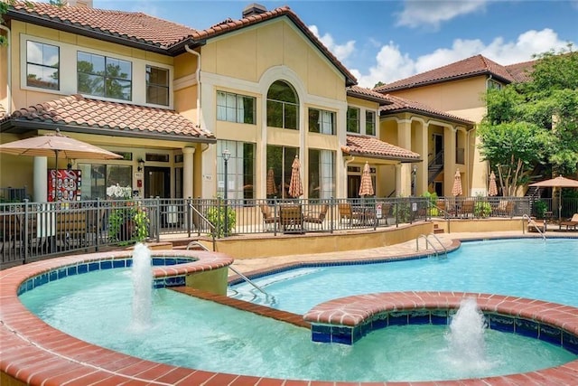 3777 Peachtree Rd NE Unit 438, Brookhaven, GA 30319 - back of property featuring a tiled roof, a chimney, stucco siding, a pool with connected hot tub, and a patio area
