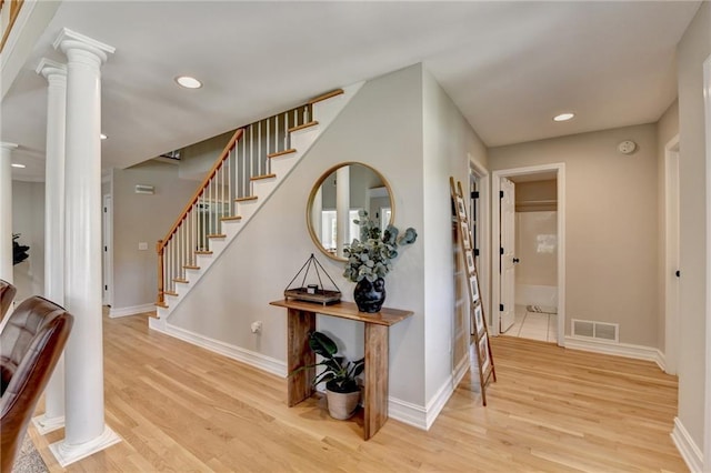 interior space featuring decorative columns, visible vents, baseboards, and wood finished floors