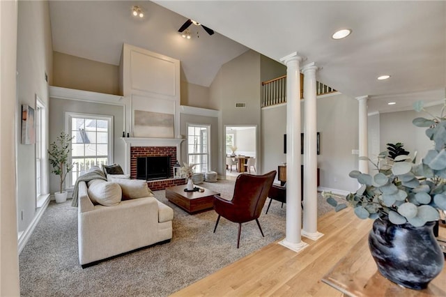 living area with baseboards, a fireplace, visible vents, ceiling fan, and decorative columns