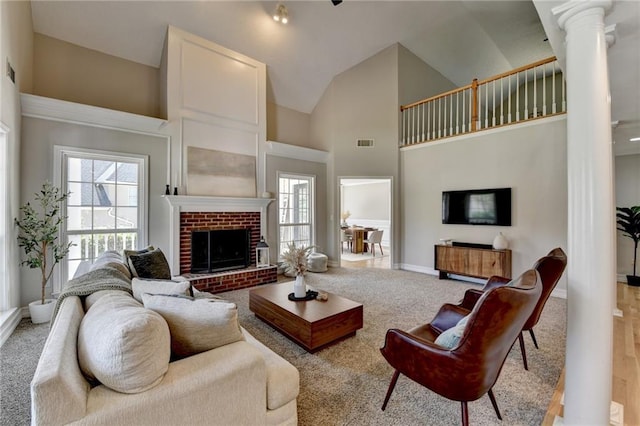 living area with visible vents, ornate columns, a brick fireplace, and a healthy amount of sunlight