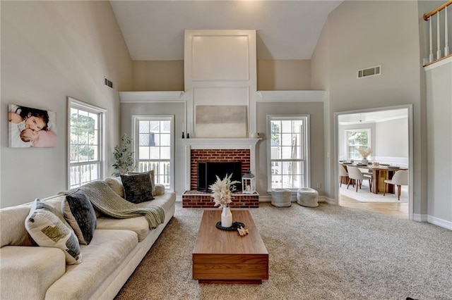 living room with visible vents, high vaulted ceiling, carpet, and a healthy amount of sunlight