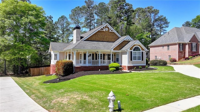 craftsman inspired home featuring a front yard, a shingled roof, a porch, a chimney, and fence