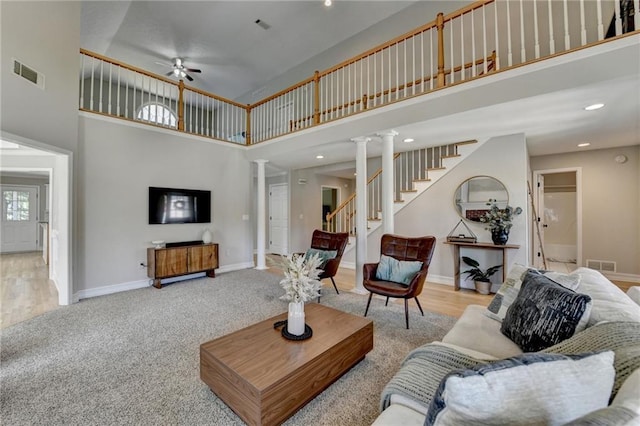 carpeted living room with ornate columns, a high ceiling, a ceiling fan, and visible vents