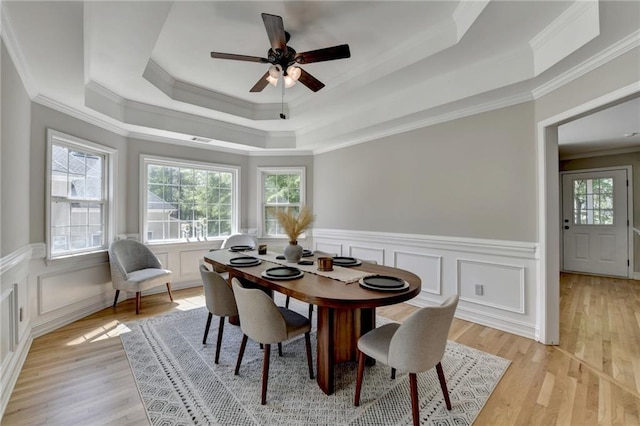 dining space with a tray ceiling, crown molding, and a healthy amount of sunlight