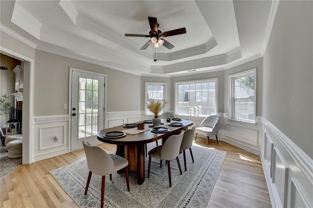 dining space with crown molding, a raised ceiling, and a healthy amount of sunlight