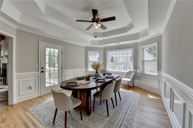 dining area with wainscoting, a tray ceiling, ornamental molding, and a ceiling fan
