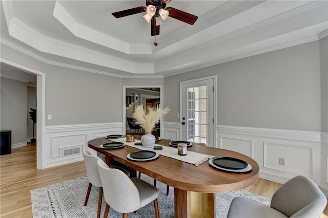 dining room with visible vents, ornamental molding, light wood-style flooring, and ceiling fan