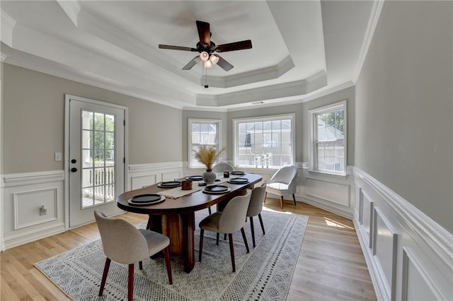dining room featuring a decorative wall, wainscoting, a tray ceiling, and crown molding