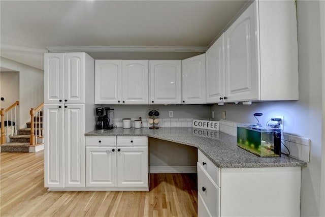 kitchen with light wood finished floors, white cabinetry, baseboards, and light stone counters
