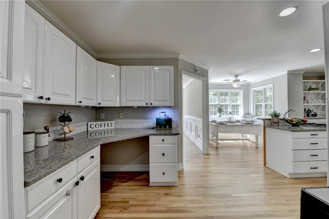 kitchen with light stone countertops, light wood-type flooring, white cabinetry, and ornamental molding