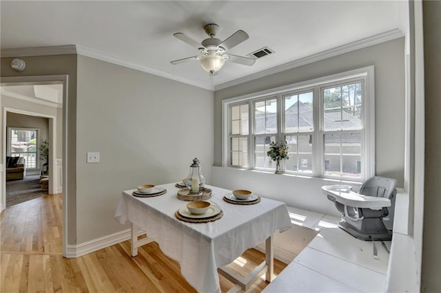 dining space featuring baseboards, crown molding, visible vents, ceiling fan, and light wood finished floors