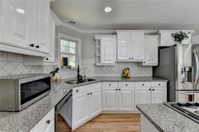 kitchen featuring white cabinets, open shelves, a sink, stainless steel appliances, and light stone counters