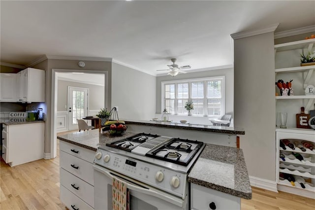 kitchen featuring dark stone countertops, white cabinets, ceiling fan, light wood-style floors, and white range with gas cooktop