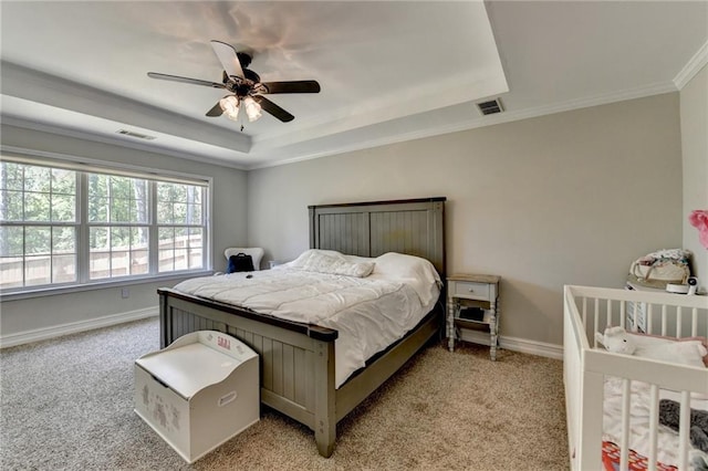 bedroom with a tray ceiling, light colored carpet, and visible vents