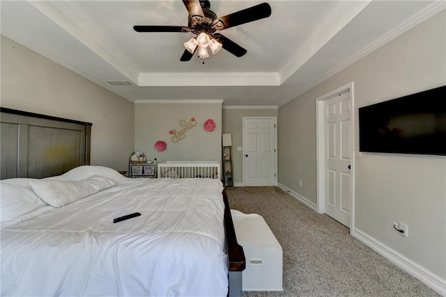 bedroom with carpet, a tray ceiling, a ceiling fan, visible vents, and ornamental molding